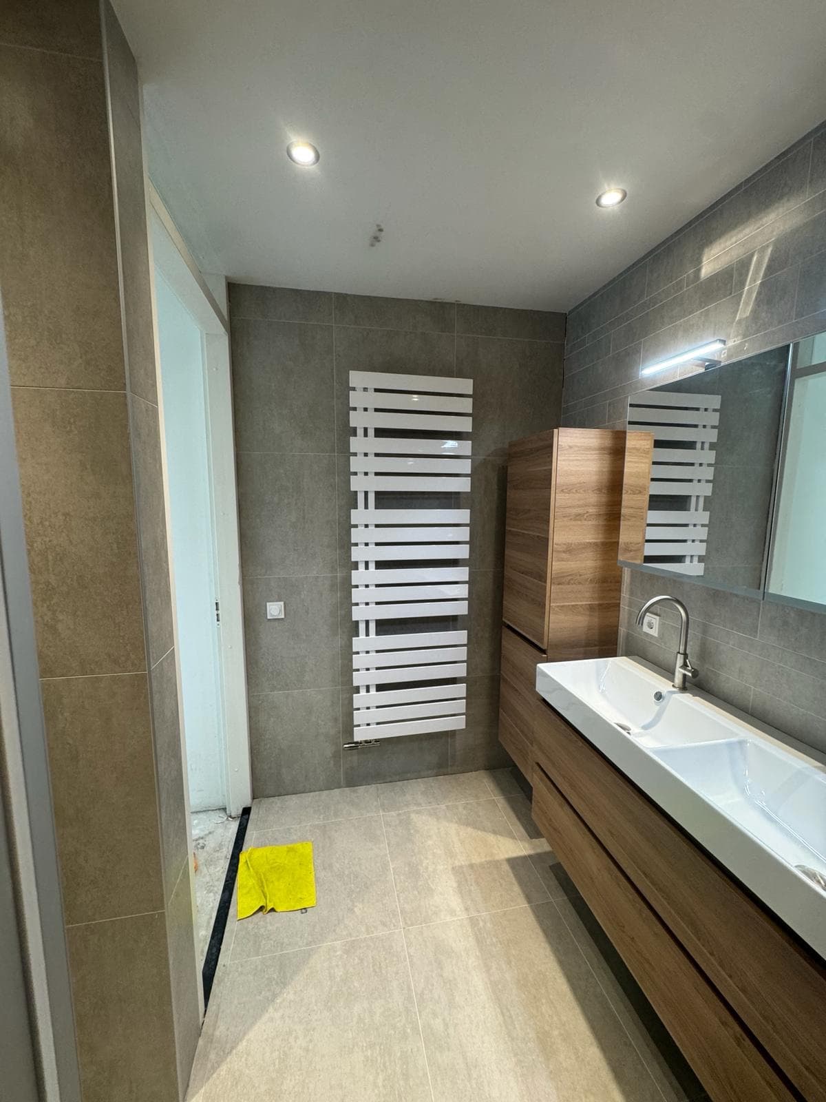Dubbele wastafel met houtkleurig meubel en witte handdoekradiator